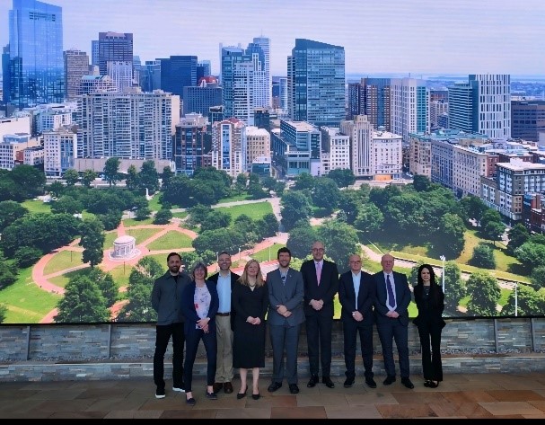 A group of people standing in front of a mural of a cityDescription automatically generated